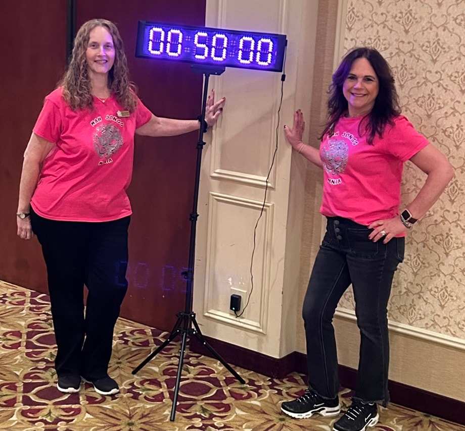 Michele and Lori standing next to the tournament countdown timer